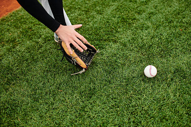 Close up of dirty baseball on grass field with palm trees in background