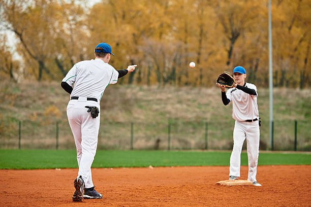 istock Two teens play an exciting baseball game on a lively afternoon field 2227510011