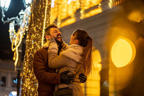 istock Happy young couple sharing a laugh under festive Christmas lights 2227518435