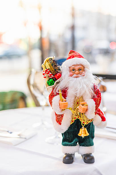istock A festive table setting with a decorative Santa Claus figurine. The table is elegantly arranged with glassware and cutlery, creating a cheerful holiday atmosphere. 2227518734