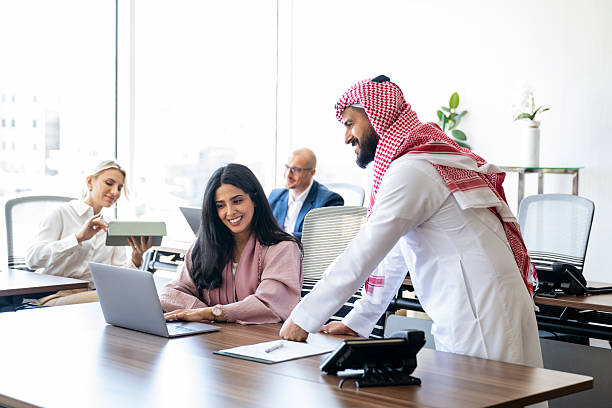 istock Cheerful Middle Eastern business manager supporting female office worker at work using laptop 2227519113