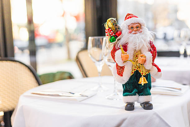 A festive table setting with a decorative Santa Claus figurine. The table is elegantly arranged with glassware and cutlery, creating a cheerful holiday atmosphere.