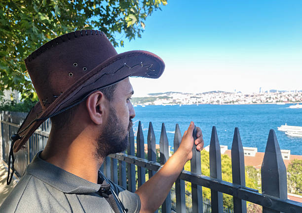 View of man in cowboy hat looking sea