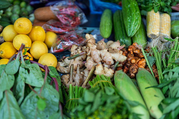 A vibrant variety of fresh vegetables, herbs, and spices on display at a traditional outdoor market in Malaysia.