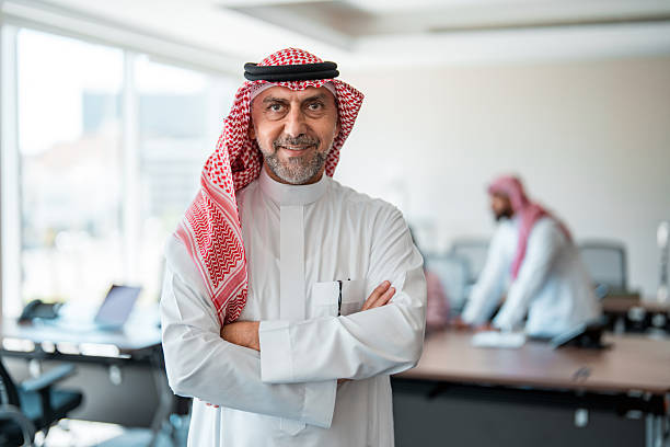 istock Confident Middle Eastern Executive In Traditional White Thobe And Red Keffiyeh Standing In Modern Office 2227521120