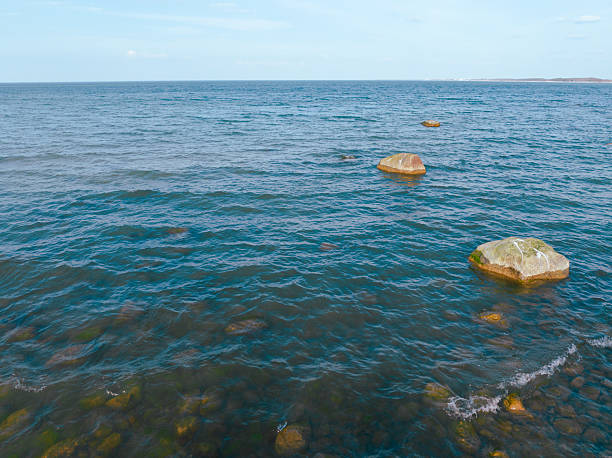 Calm turquoise waters with visible rocks and marine vegetation beneath the surface in a coastal area.