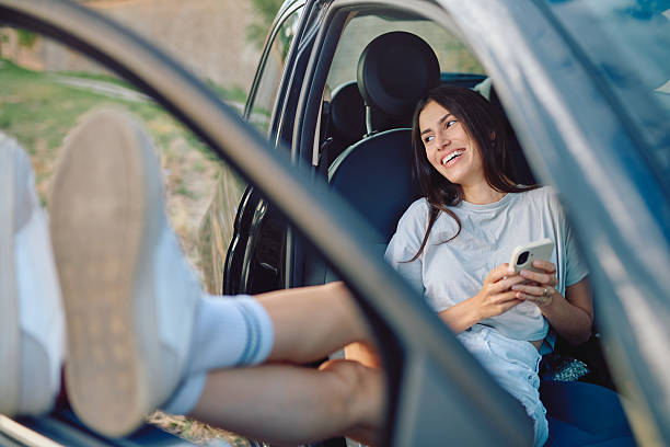 istock Young woman is using her smartphone while relaxing in a car with her feet up 2227525366
