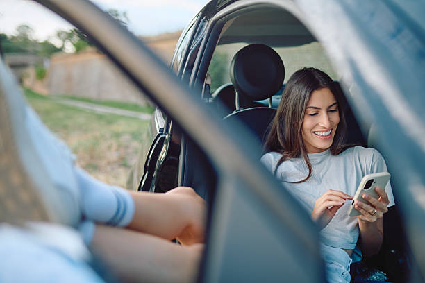 istock Young woman using mobile phone while relaxing in car during road trip 2227525381