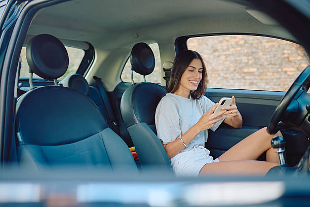 istock Young woman using mobile phone while sitting in car 2227525456