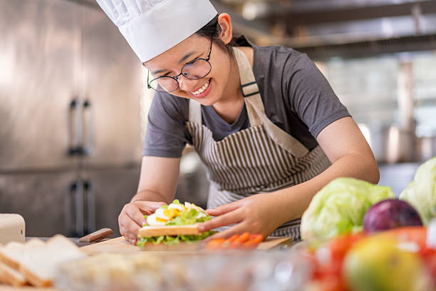 istock Smiling Young Female Chef Preparing a Sandwich in a Professional Kitchen 2227525706