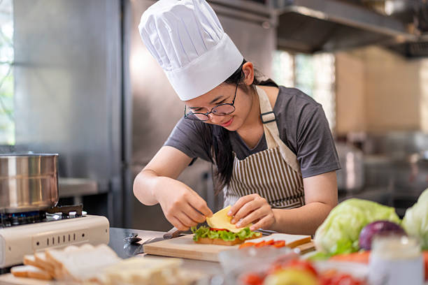 istock Smiling Young Female Chef Preparing a Sandwich in a Professional Kitchen 2227525901