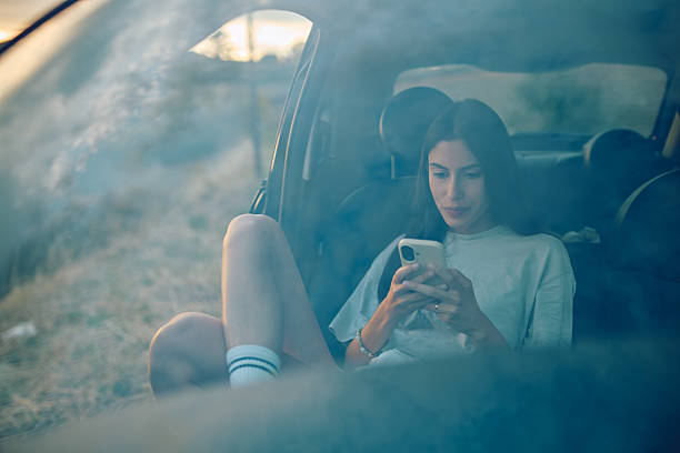 istock Young woman using mobile phone inside car seen through window 2227525936