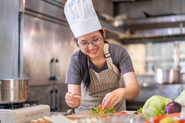 istock Smiling Young Female Chef Preparing a Sandwich in a Professional Kitchen 2227526089