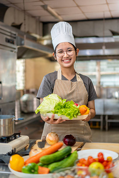 istock Happy Young Asian Female Chef Holding Fresh Vegetables 2227526623