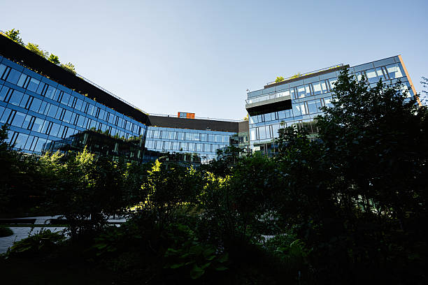 istock Modern glass office building surrounded by lush greenery under a clear sky 2227526830