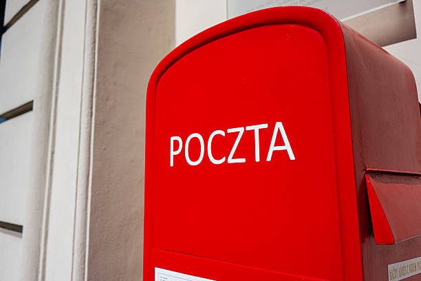 A red Polish mailbox marked 'Poczta' situated outdoors on a sunny day
