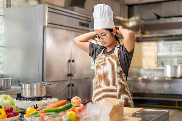 istock Young Asian Female Chef Adjusting Hat in Professional Kitchen 2227527358