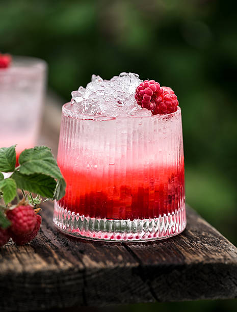 istock Chilled raspberry cocktail with ice cubes placed outdoors against natural background of lush raspberry bushes. Summer drink concept 2227528261