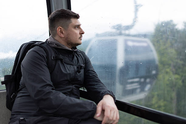 A man rides in a funicular trailer on a cloudy day