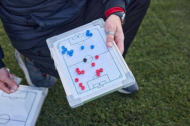 Close-up view of hands holding a clipboard with soccer diagrams.