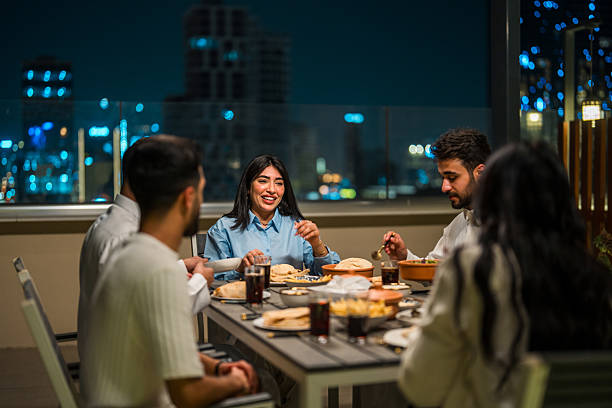 istock Cheerful Arabic Friends Enjoying Rooftop Dinner Under Riyadh's Night Sky 2227533052