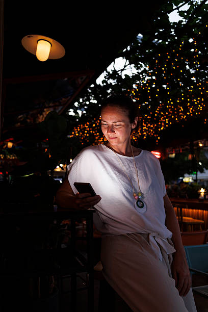 istock Woman using smart phone while relaxing in a cafe on a night out 2227535523