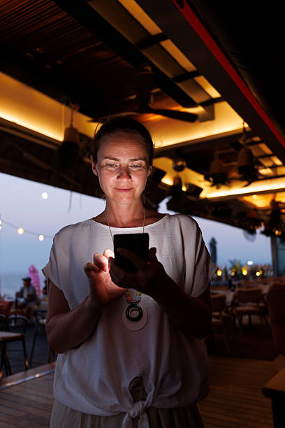 istock Woman using smart phone while relaxing in a cafe on a night out 2227535536