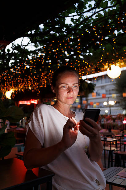 istock Woman using smart phone while relaxing in a cafe on a night out 2227535675