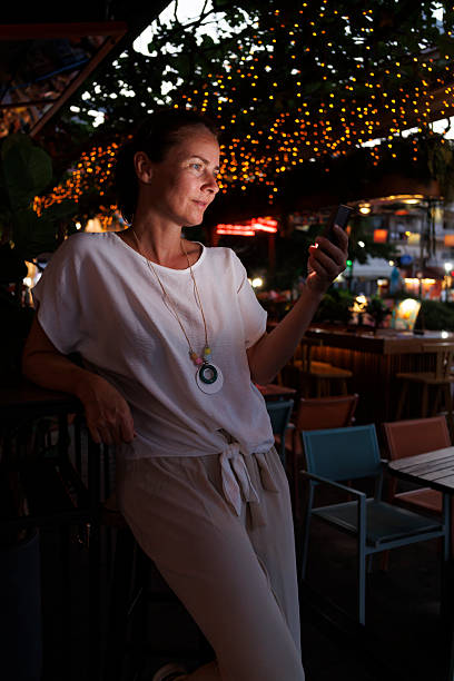 istock Woman using smart phone while relaxing in a cafe on a night out 2227535691