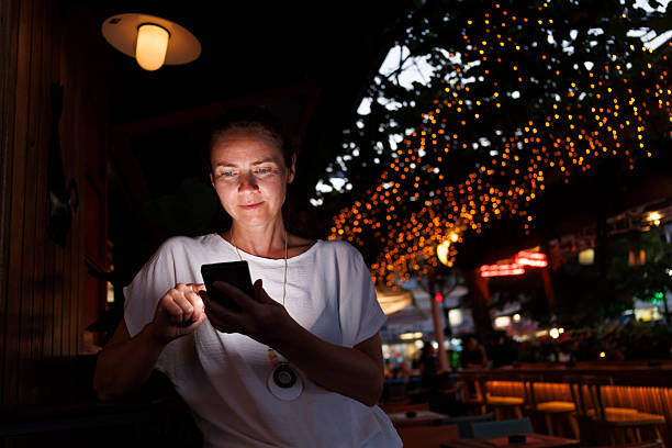 istock Woman using smart phone while relaxing in a cafe on a night out 2227535793