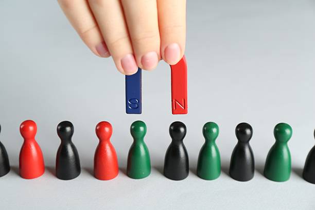 istock Woman with magnet attracting different game pieces at white table, closeup 2227541233
