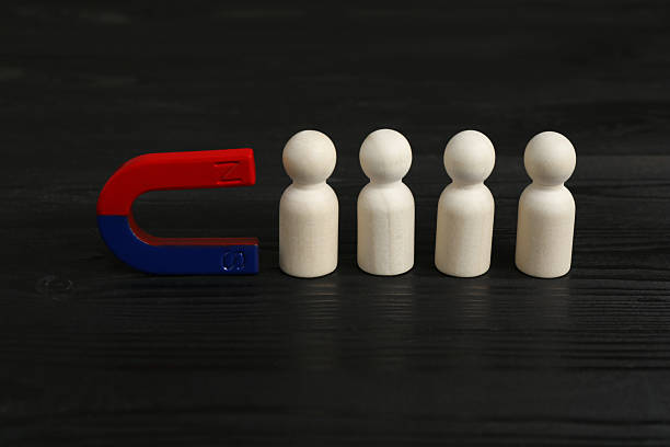 istock Magnet attracting human figures on black wooden table 2227541408