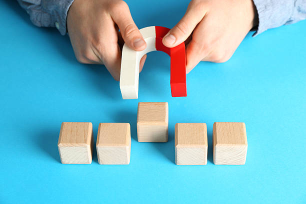 istock Man with magnet attracting wooden cubes on light blue background, closeup 2227541455