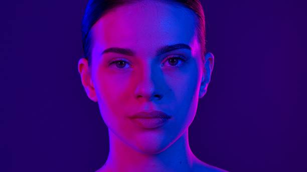 A striking portrait of a person under vibrant neon lighting, creating a captivating mix of blue and pink hues.