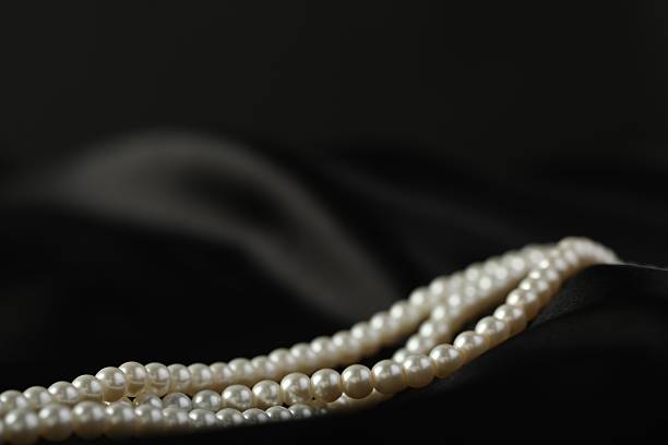 White and pink pearls on the black silk as background