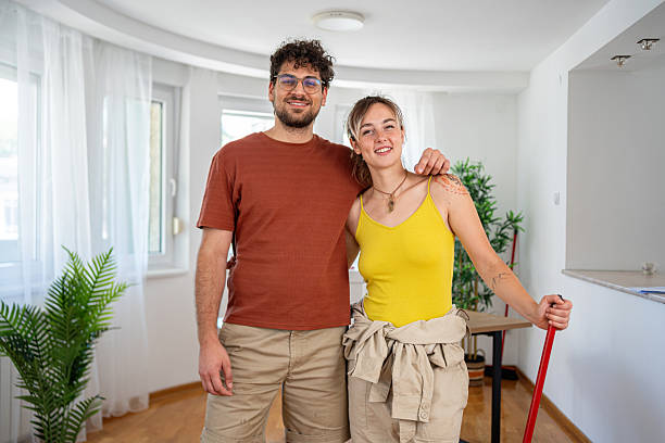 istock Happy couple smiling while cleaning their modern apartment together 2227542882