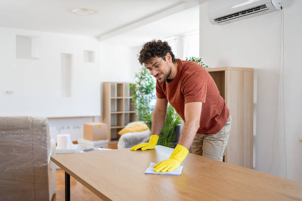istock Man maintaining cleanliness by wiping wooden table in bright home 2227543746