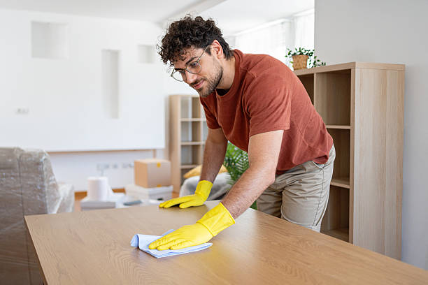 istock Man cleaning a wooden table in a well-lit apartment using a cloth 2227544054