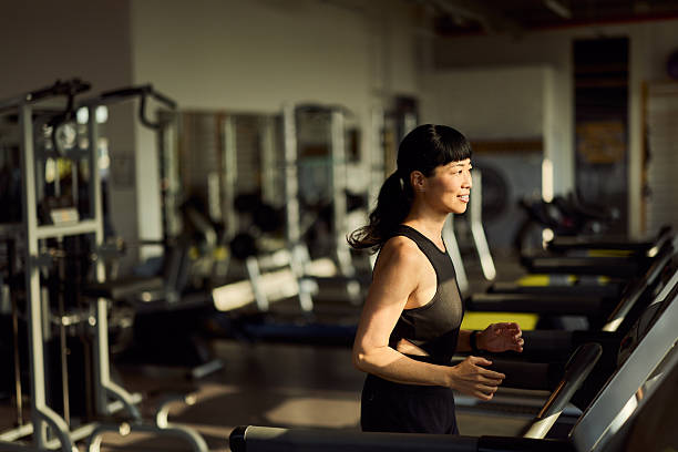 istock Woman Running on a Treadmill at a Brightly Lit Modern Gym 2227544263