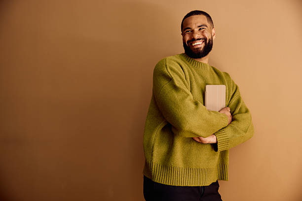 istock Cheerful young business man holding a digital tablet while standing against a plain brown wall in a minimalist office 2227544531