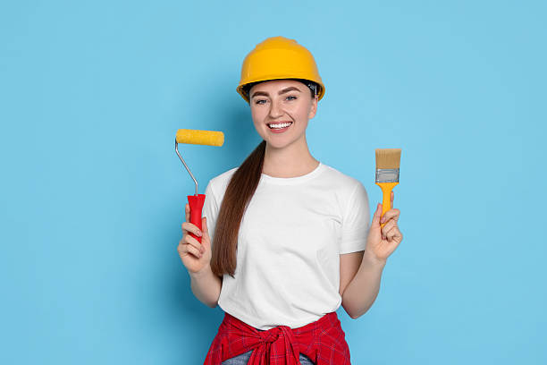 istock Portrait of young decorator with paint roller and brush on light blue background 2227546430