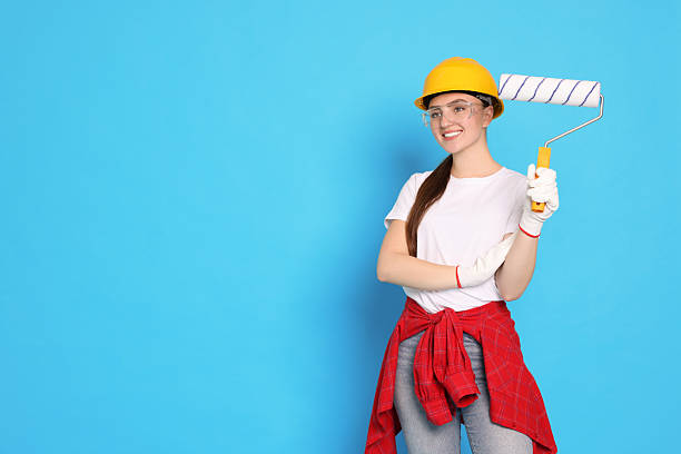 istock Portrait of young decorator with paint roller on light blue background, space for text 2227546472