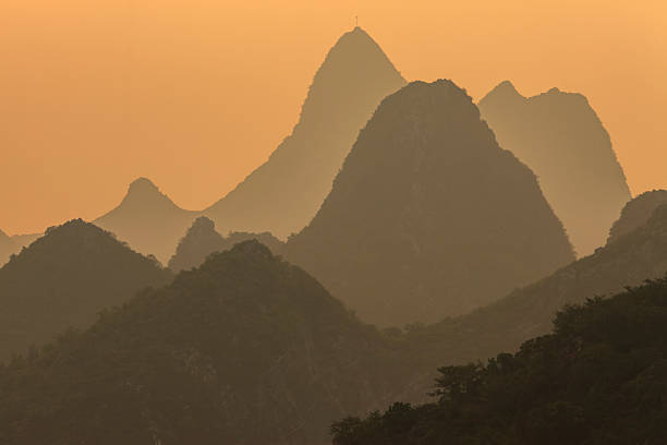 A view of the strange peaks from Guilin at dusk. Illuminated by the soft setting sun, the karst mountains create a mystical silhouette.