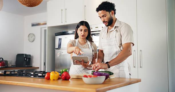 istock Couple, cooking and tablet with online recipe in kitchen for meal instructions, tutorial guidance or support. People, food blog or cutting ingredients for healthy dinner or nutrition website in home 2227550913