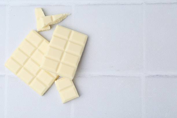 istock Pieces of delicious white chocolate on tiled table, top view. Space for text 2227552531