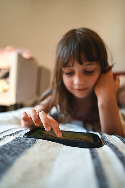 istock Young girl playing with smartphone on bed at home 2227555213