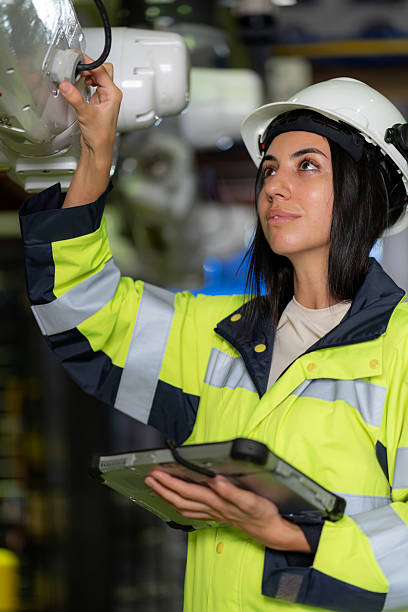 In a cutting-edge manufacturing facility, a female engineer ensures the robotic arm meets safety and performance standards. Combining expertise and robotics, she bridges the gap between human intelligence and automated systems.
