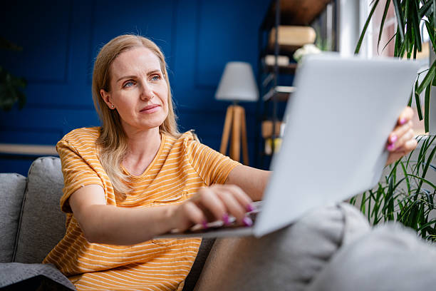 istock Woman enjoying technology while relaxing on sofa in cozy living room 2227558085