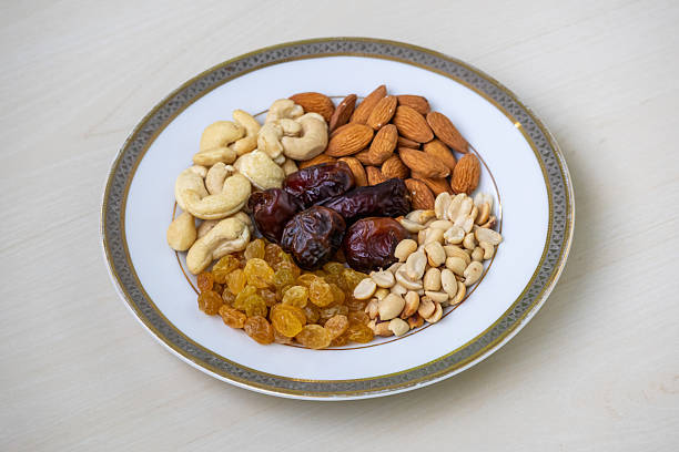 Assorted healthy nuts and dried fruitsalmonds, cashews, peanuts, dates, raisinsartfully arranged on a clean white plate. Perfect for wellness and healthy lifestyle themes.