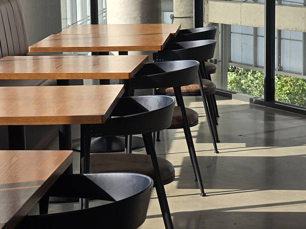 istock Modern dining area with wooden tables and black chairs, featuring large windows that allow natural light to illuminate space. minimalist design creates welcoming atmosphere 2227561686